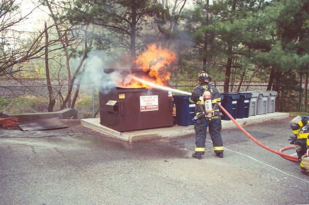 FF/EMT Ferraro attacks a dumpster fire with an 1 1/2&quot; handline.